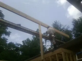Carpenter setting a ridge beam over a new addition frame — Ice Dam Removal by Roofing Brothers in Mc Dade