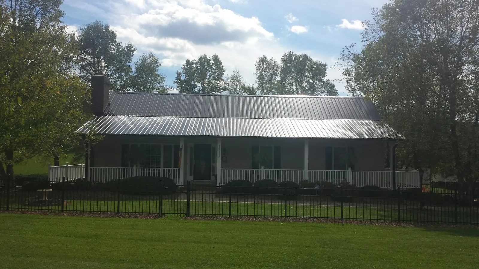 Gray metal roof on a brick ranch with a full width front porch — Gutter Guard Installation work by our crew in Mc Dade